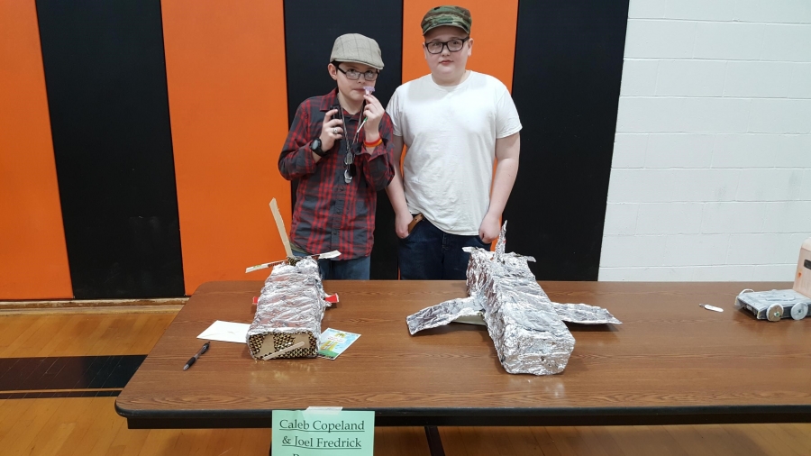 two boys standing behind a table